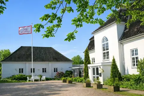 TaxGården, hvid patriciervilla i Bagsværd med flag og grønne omgivelser